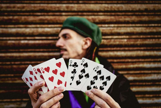 Red heart and black spade playing cards held by a person